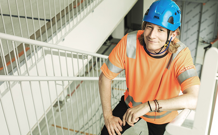 Nuori rakennusmies kiipeää portaita. ylös.